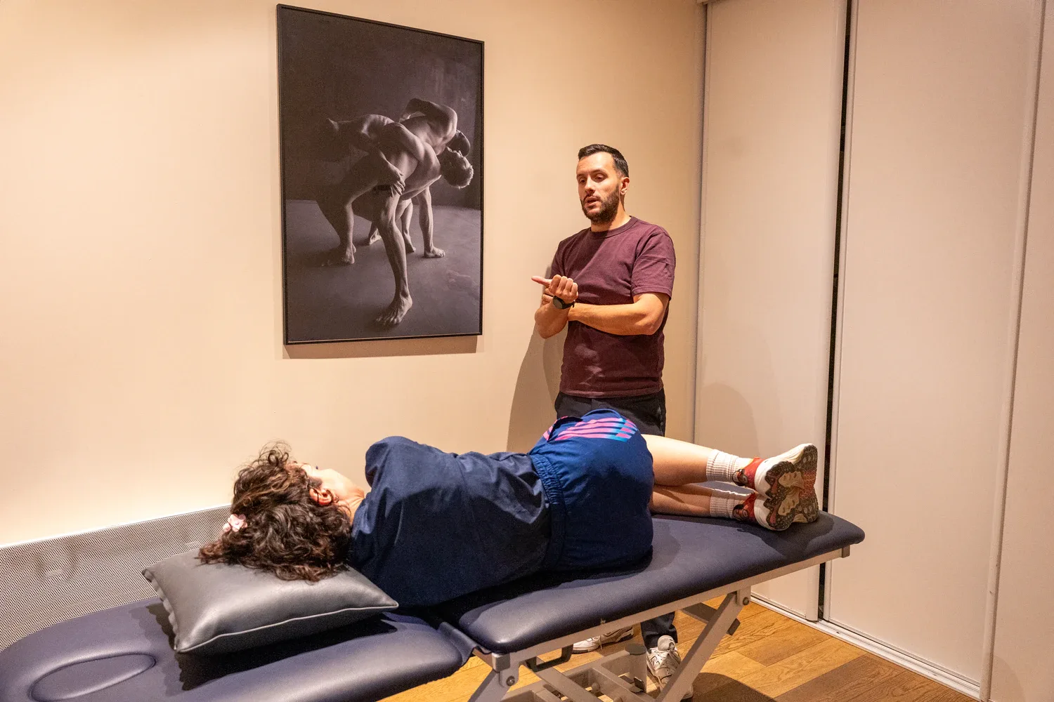 Man instructs during therapy session with patient on table.