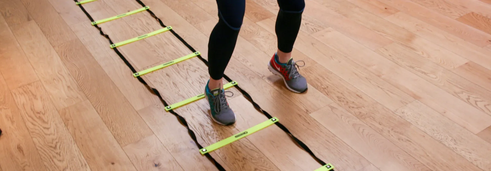 Person using agility ladder for exercise indoors.